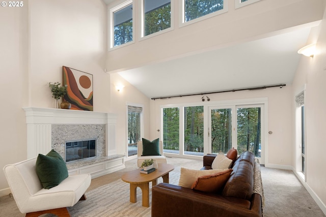 living room with a high ceiling, a premium fireplace, a healthy amount of sunlight, and light colored carpet