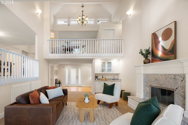 living room featuring an inviting chandelier, a fireplace, french doors, and a high ceiling