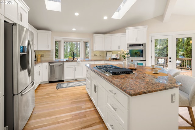 kitchen featuring a kitchen island, appliances with stainless steel finishes, sink, a breakfast bar area, and white cabinets