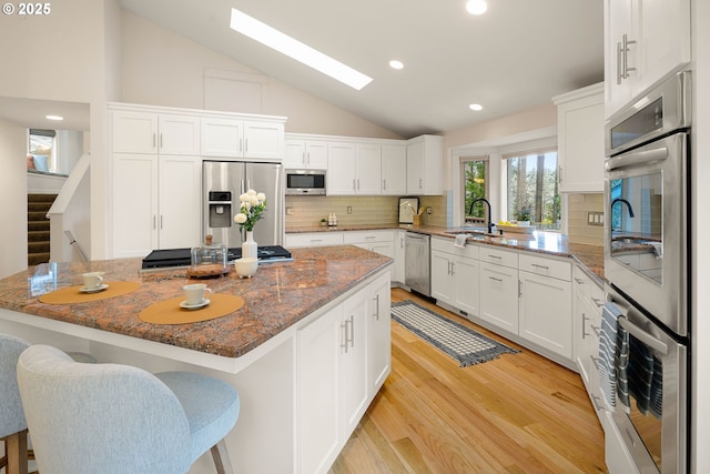 kitchen with white cabinetry, appliances with stainless steel finishes, a center island, and stone counters