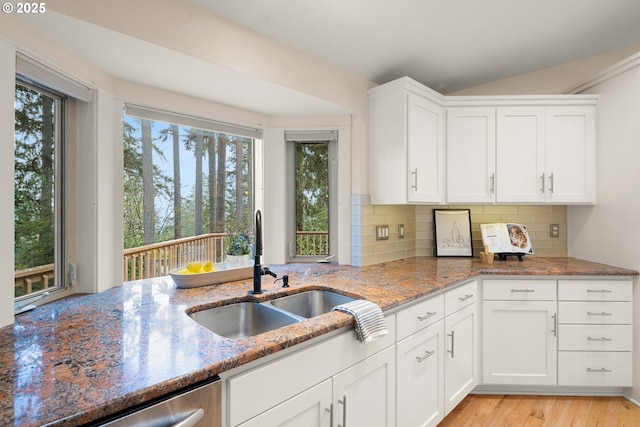 kitchen with stone counters, a healthy amount of sunlight, sink, and white cabinets