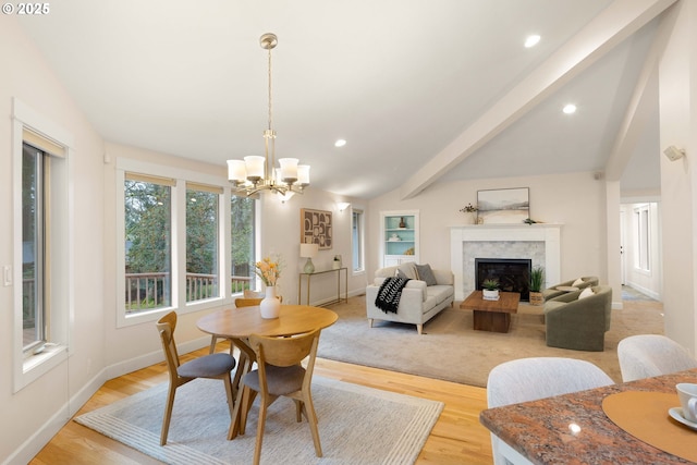 dining room featuring a notable chandelier, a fireplace, lofted ceiling with beams, and light wood-type flooring