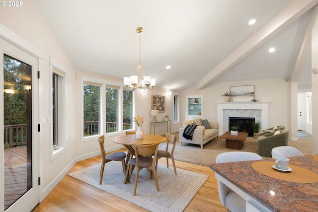 dining room with lofted ceiling with beams, a premium fireplace, and light wood-type flooring