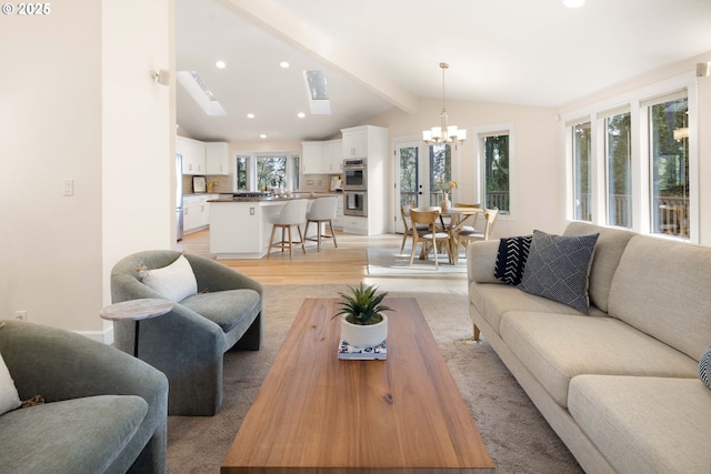 living room featuring lofted ceiling with beams, light hardwood / wood-style floors, and a chandelier