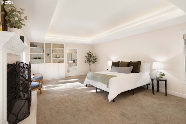 carpeted bedroom featuring a raised ceiling and ensuite bathroom