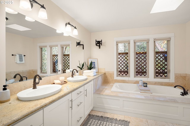 bathroom with vanity, a bath, a skylight, and tile patterned floors