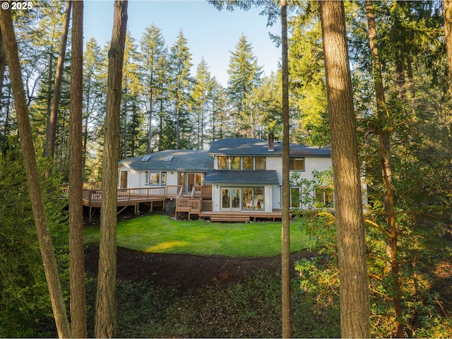 rear view of house featuring a wooden deck and a lawn