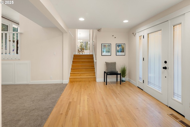 foyer entrance with light carpet and a notable chandelier