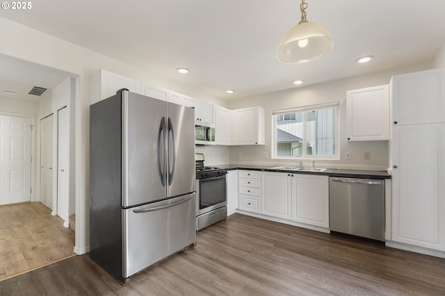 15629 NW Energia St, Portland, OR 97229 - kitchen featuring appliances with stainless steel finishes, wood finished floors, white cabinets, dark countertops, and recessed lighting