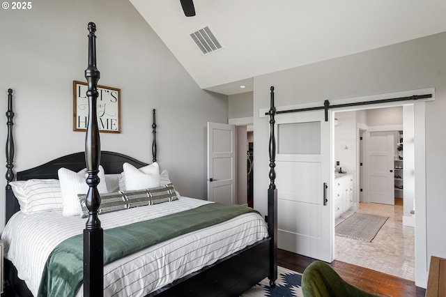 4040 Victor Point Rd NE, Silverton, OR 97381 - bedroom featuring high vaulted ceiling, a barn door, wood finished floors, and a ceiling fan