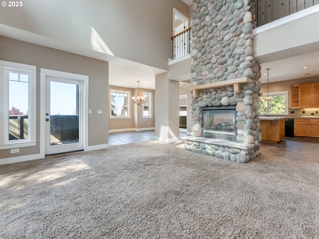 10193 SE Crescent Ridge Loop, Happy Valley, OR 97086 - unfurnished living room with a chandelier, carpet floors, a stone fireplace, healthy amount of natural light, and a high ceiling