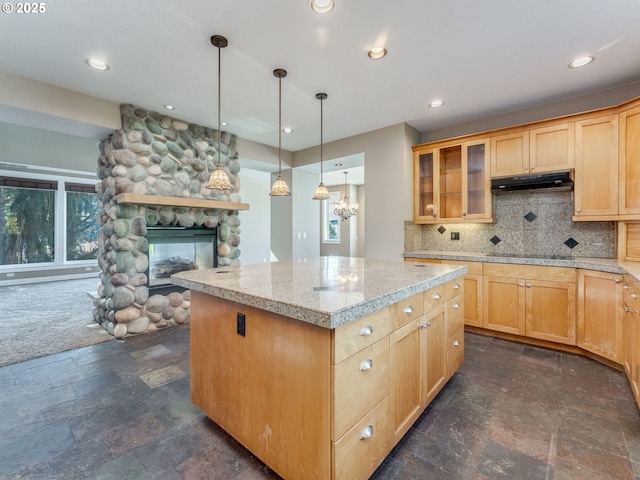 10193 SE Crescent Ridge Loop, Happy Valley, OR 97086 - kitchen featuring under cabinet range hood, a fireplace, a center island, tasteful backsplash, and dark stone finish flooring
