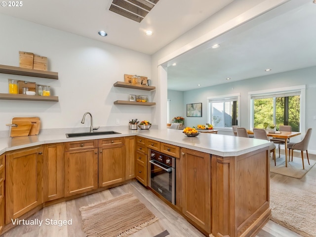 10193 SE Crescent Ridge Loop, Happy Valley, OR 97086 - kitchen with oven, open shelves, a peninsula, light wood-style flooring, and light countertops