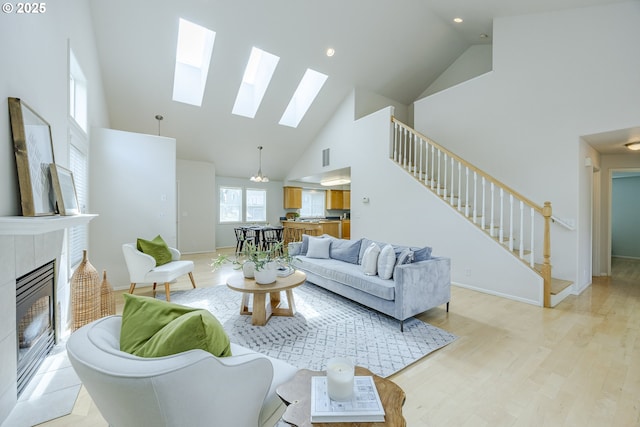 3618 Sterling Woods Dr, Eugene, OR 97408 - living room featuring high vaulted ceiling, a skylight, stairway, a fireplace, and light wood-style flooring
