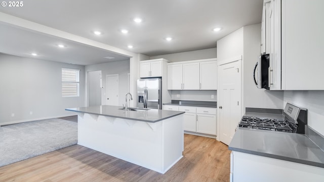 kitchen with dark countertops, appliances with stainless steel finishes, light wood-style flooring, and a sink