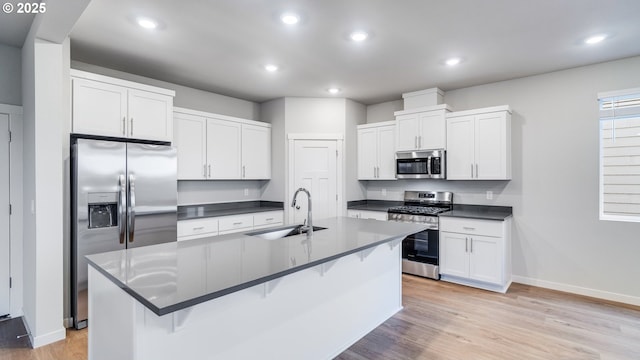 kitchen with dark countertops, appliances with stainless steel finishes, baseboards, and a sink