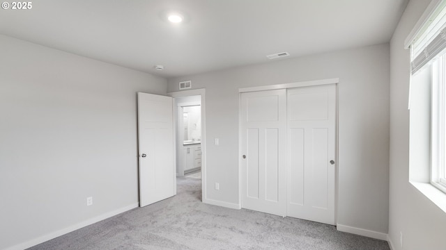 unfurnished bedroom featuring baseboards, visible vents, and light colored carpet