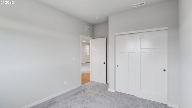 unfurnished bedroom with a closet, visible vents, baseboards, and carpet floors