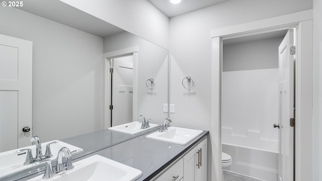 bathroom with double vanity, toilet, and a sink