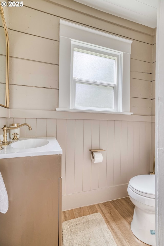 51 N Dean St, Coquille, OR 97423 - half bath with vanity, wooden walls, toilet, and wood finished floors