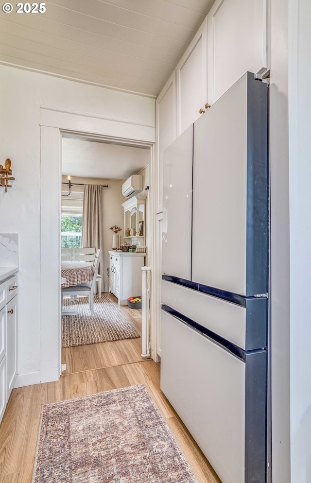 51 N Dean St, Coquille, OR 97423 - kitchen with freestanding refrigerator, a wall unit AC, light wood-style floors, white cabinetry, and light countertops