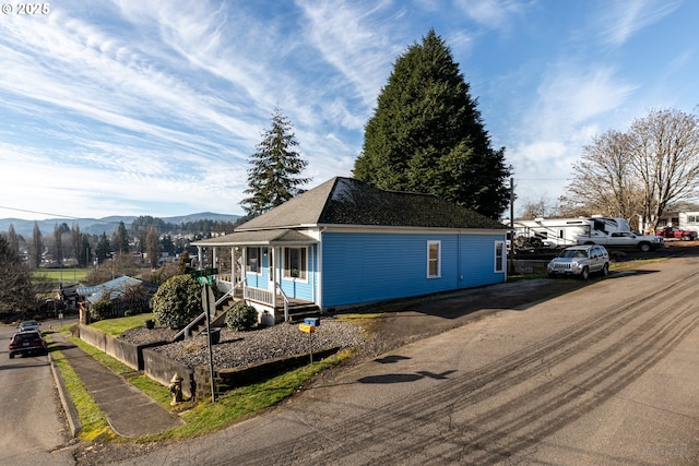 view of side of property with a mountain view and covered porch