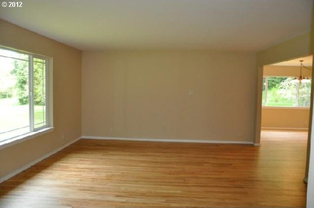 unfurnished room with light wood-style floors, a notable chandelier, and baseboards