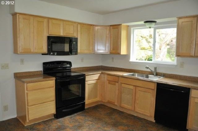 kitchen with black appliances, light brown cabinets, light countertops, and a sink