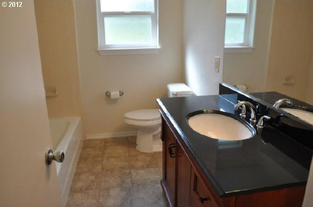 bathroom with toilet, baseboards, vanity, and a healthy amount of sunlight