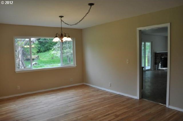 unfurnished room featuring baseboards, a chandelier, and wood finished floors