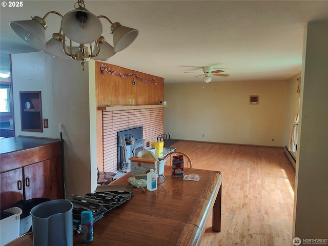 3420 Prill Rd, Centralia, WA 98531 - living area featuring baseboard heating, a ceiling fan, a brick fireplace, and wood finished floors
