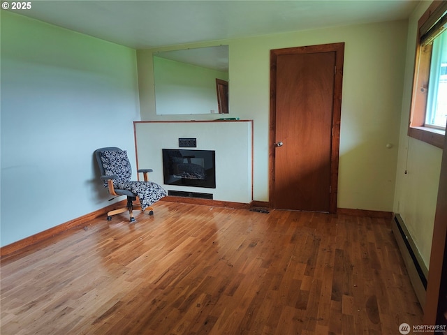 3420 Prill Rd, Centralia, WA 98531 - living area with wood finished floors, baseboard heating, a glass covered fireplace, and baseboards