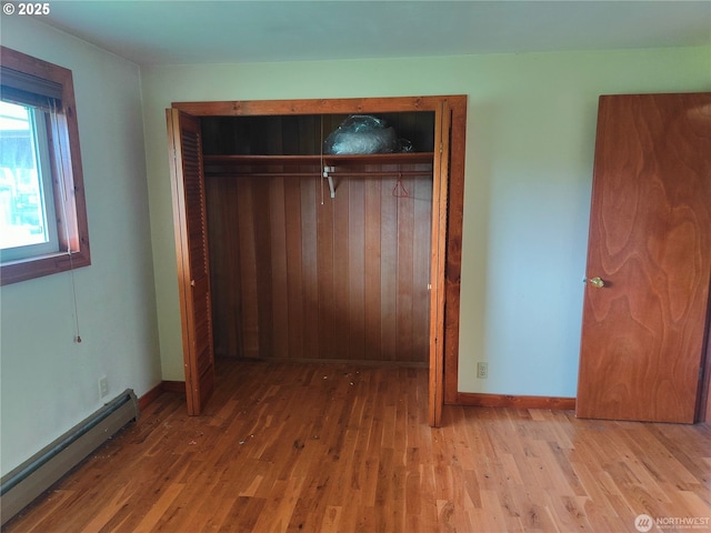 3420 Prill Rd, Centralia, WA 98531 - unfurnished bedroom featuring a baseboard heating unit, a closet, wood finished floors, and baseboards