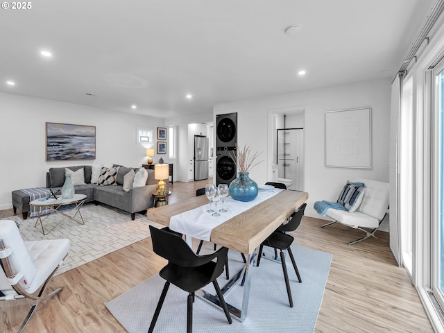 dining space with stacked washer and clothes dryer and light hardwood / wood-style flooring