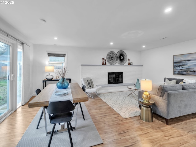 living room with a brick fireplace and light hardwood / wood-style floors