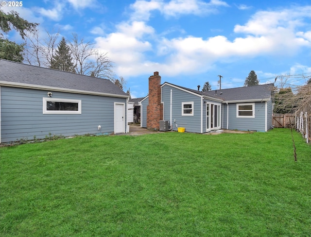 rear view of property featuring cooling unit and a lawn