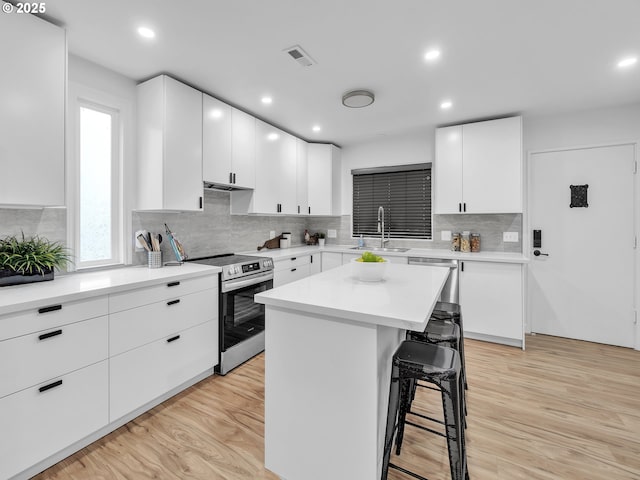 kitchen featuring a breakfast bar area, stainless steel appliances, a kitchen island, sink, and white cabinetry