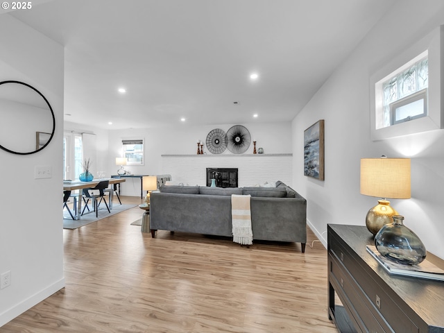 living room featuring light wood-type flooring and a brick fireplace