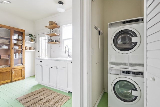 laundry room with stacked washing maching and dryer, light hardwood / wood-style floors, and sink