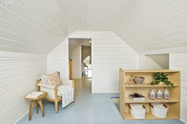 living area with lofted ceiling, wood ceiling, and wooden walls