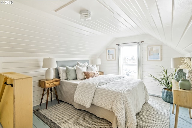 bedroom with lofted ceiling and wood walls