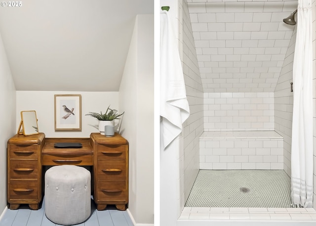 bathroom with a tile shower and lofted ceiling