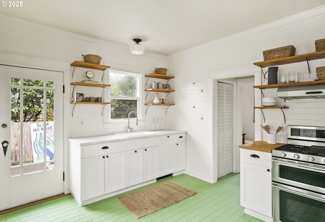 kitchen featuring extractor fan, sink, range with two ovens, and white cabinets