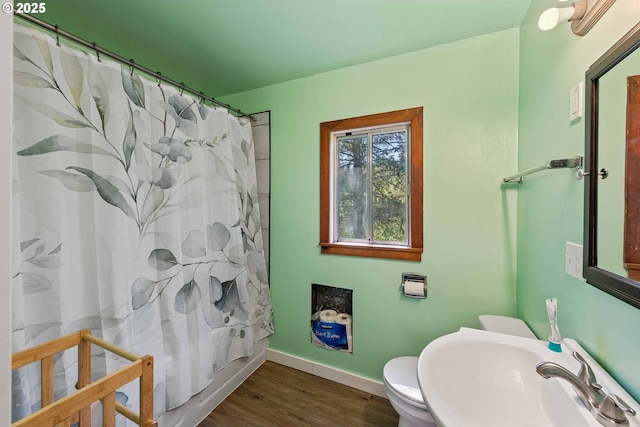 bathroom with a sink, wood finished floors, baseboards, toilet, and a shower with curtain