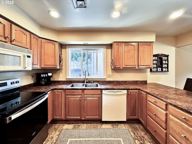 kitchen with white appliances, dark countertops, and a sink