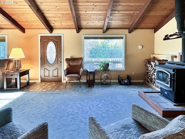 carpeted living room featuring lofted ceiling with beams, a wood stove, wood ceiling, and baseboards