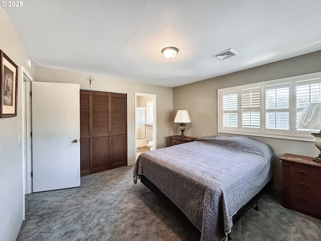 carpeted bedroom featuring ensuite bath, visible vents, a closet, and a textured ceiling