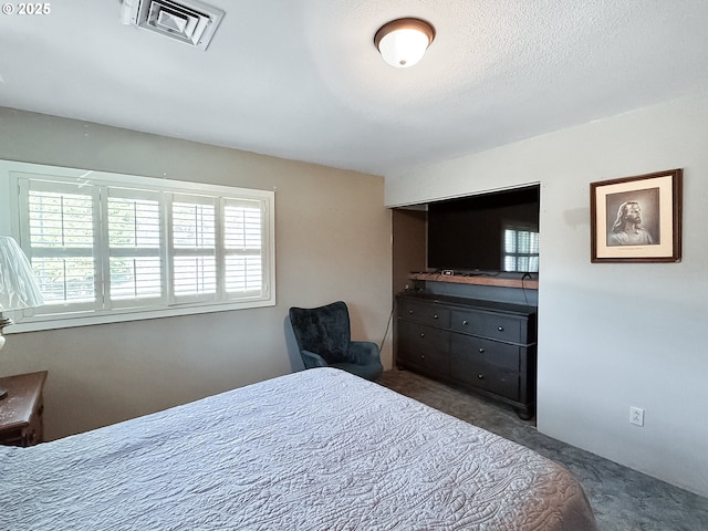 carpeted bedroom with visible vents and a textured ceiling