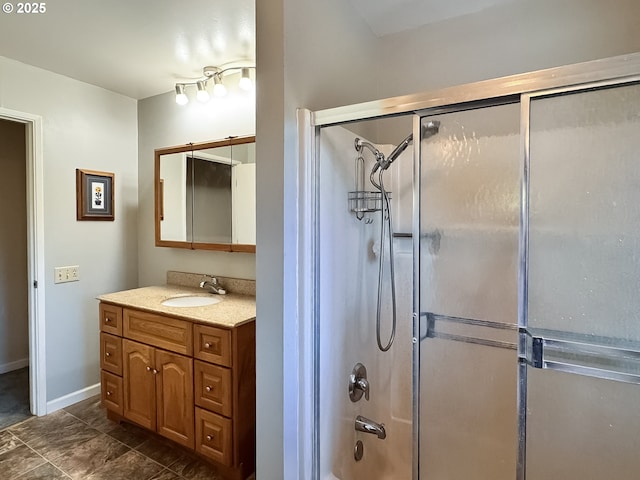 bathroom featuring combined bath / shower with glass door, baseboards, and vanity