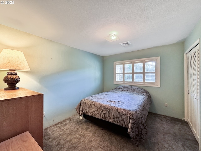 bedroom featuring visible vents, a textured ceiling, a closet, and carpet